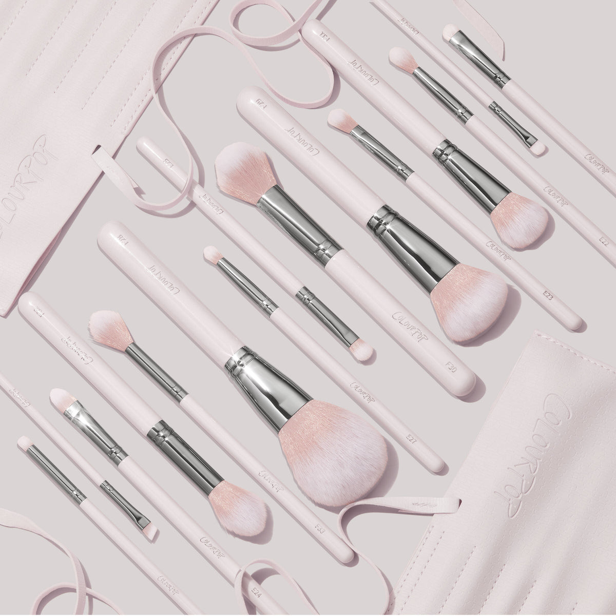 Stone Cold ColourPop Makeup Brush Kit showcasing soft pink powder, blush, and eye brushes with silver ferrules, laid out in a flat lay beside a matching roll-up brush case on a pale backdrop.