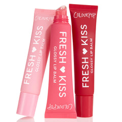 ColourPop Glossy Lip Balm Trio Fruit Basket shows three Fresh Kiss tubes - pastel pink, bright pink uncapped with slanted applicator, and deep red - standing side by side on a white background with white branding.