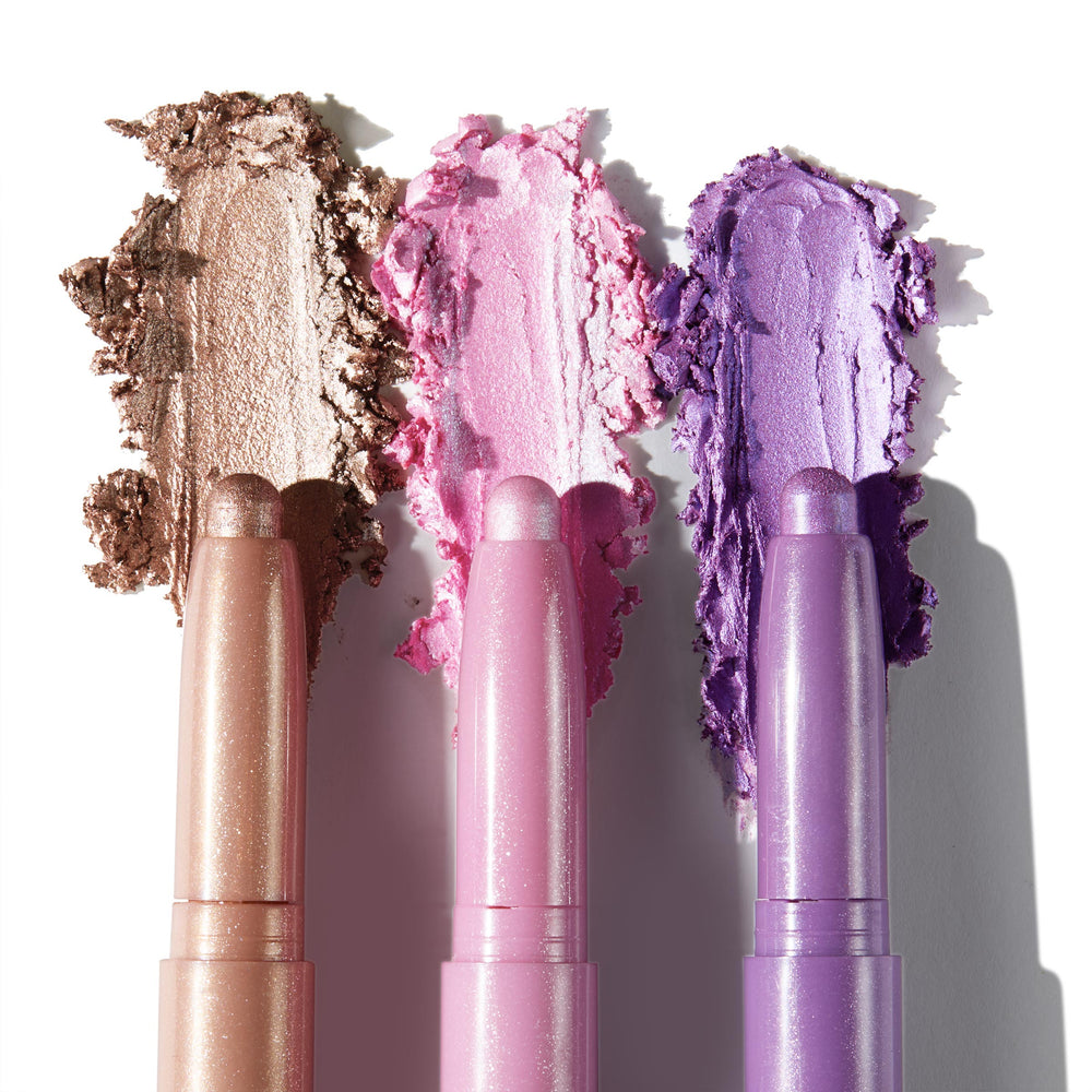 ColourPop Shadow Stix Cool Metallics eyeshadow trio displayed with creamy shimmer swatches - champagne taupe, icy pink, and lavender purple - smeared behind the sticks on a white background for shade comparison.