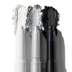 ColourPop Shadow Stix Totally Wicked trio shows uncapped pencils with rich swatches - matte white, metallic silver, and matte black - smeared behind each tip on a white background for bold smoky or graphic eye looks.