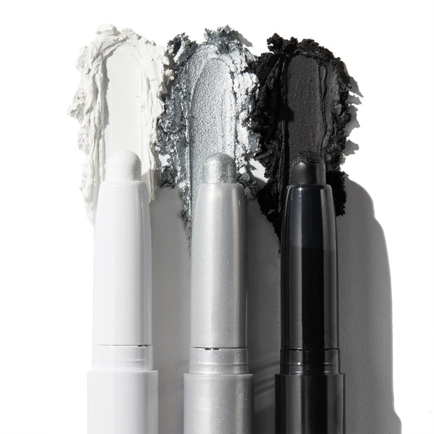 ColourPop Shadow Stix Totally Wicked trio shows uncapped pencils with rich swatches - matte white, metallic silver, and matte black - smeared behind each tip on a white background for bold smoky or graphic eye looks.