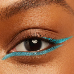 Electric-blue winged liner sweeping along upper and lower lashes on a close-up eye, showcasing Out of the Blue Crème Gel Liner from ColourPop; sharp cat-eye on warm medium skin using ColourPop Crème Gel Liner.
