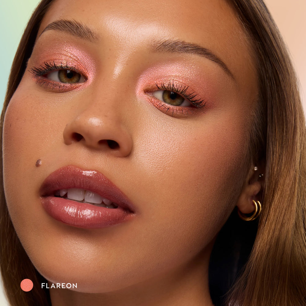 Model with medium skin wearing Flareon tangerine Multichrome Shadow Stix on the lids