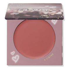 ColourPop Cream Blush A-Lister compact displaying a warm rosy-mauve pan, lid half-closed with bokeh print, set in lavender packaging with heart doodles and gold A-LISTER text, studio-lit on a white background.