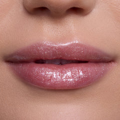 Close-up of lips wearing Bright Ariel Ultra Glossy Lip, a shimmering pink Disney Princess lip gloss with high-shine, reflective sparkle on smooth, fair skin, showcasing moisturizing, ultra-glossy finish for everyday glam makeup looks.