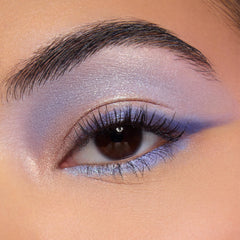 Shimmery lavender-to-blue winged eyeshadow accenting a brown eye, with an iridescent inner corner and lilac lower lash line, showcasing shades from the Disney Lilo and Stitch Collection ColourPop Full Collection Set in a close-up beauty shot.