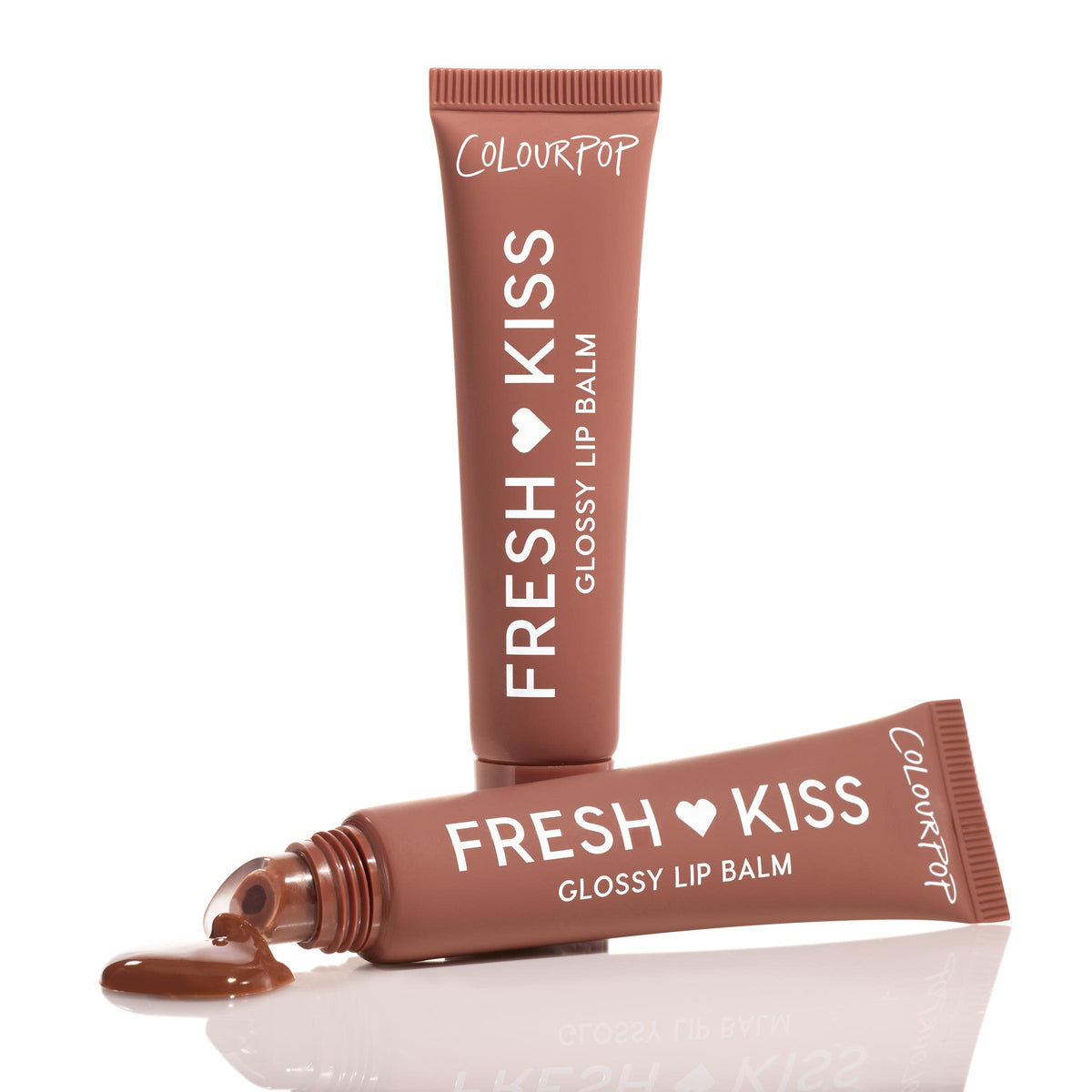 ColourPop Fresh Kiss Glossy Balm in Chocolate Milkshake shown in studio: one warm cocoa-brown squeezy tube upright and another horizontal with gloss pooling from the tip on a reflective white surface, showcasing the creamy high-shine formula and white lettering.