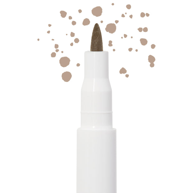 Soft Brown freckle pen by Colourpop with a fine felt tip applying natural soft brown dots, shown close up against a white background to highlight precise faux freckle makeup for the face.