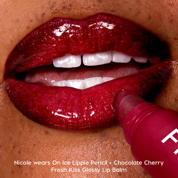 Close-up of glossy, deep red lips as Colourpop Fresh Kiss Glossy Balm in Chocolate Cherry is applied, showcasing high-shine Lip Gloss & Lip Oil texture against smooth brown skin.