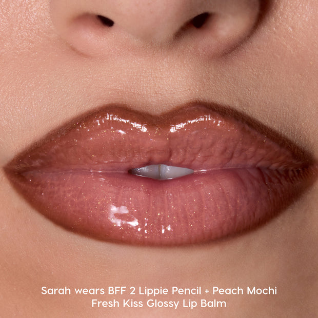 Close-up glossy lips wearing Colourpop Peach Mochi Fresh Kiss Glossy Balm, showing sheer peachy nude shine with subtle shimmer, highlighting smooth, hydrated finish ideal for Lip Gloss & Lip Oil lovers.