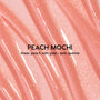 Colourpop Fresh Kiss Glossy Balm in Peach Mochi swatched in smooth, wavy streaks, showing a sheer peach Lip Gloss & Lip Oil texture with fine gold and pink sparkle against a close-up shimmering background.
