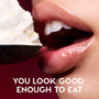 Close-up glossy lips wearing Colourpop Fresh Kiss Glossy Balm in Whipped Cream hover near a spoonful of whipped cream against a pink background, showcasing the shimmery Lip Gloss & Lip Oil texture with slogan “You look good enough to eat.”