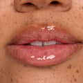 Glossy pink lips wearing a clear, high-shine lip treatment, captured in a tight macro on freckled skin; hydrating sheen and smooth texture showcased as a ColourPop beauty swatch for a plump, moisturized finish.