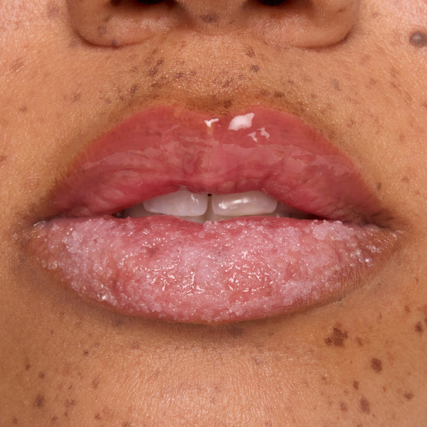 Glossy lips buffed with a candy cane sugar scrub while a hydrating mask coats the top lip, showcasing Colourpop Merriest Pout lip set in action, close-up on freckled skin to highlight smooth, exfoliated results.