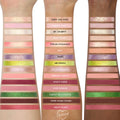 ColourPop How the Grinch Stole Christmas shadow palette swatched on three forearms, showing 18 labeled shades - neutrals, pinks, cranberry, purple, metallic golds, lime green, and deep brown - demonstrating payoff across light to deep skin tones.