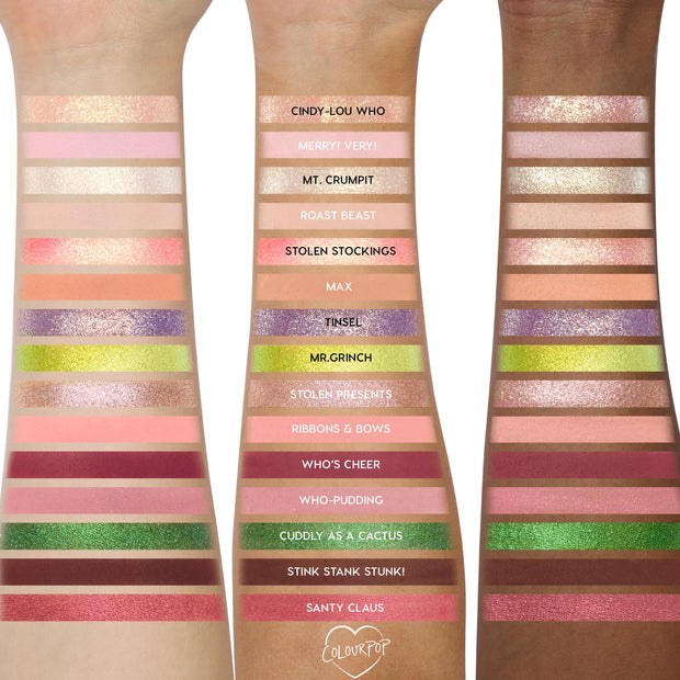 Grinch Glam Shadow Palette + Glitter Gel swatched across three arms, showing matte and glitter pinks, greens, golds, and plums with labeled shades like Mr. Grinch, Tinsel, and Santy Claus; festive ColourPop arm swatches for holiday eye looks.