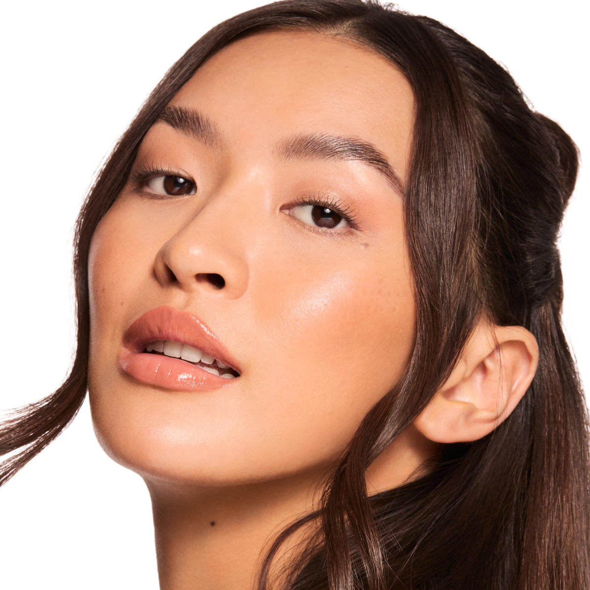Glossy nude lips wearing Caramel Latte Fresh Kiss Glossy Balm, delivering hydrating shine and a sheer warm caramel tint; full-face close-up of a model with dewy skin and brunette waves on a white studio background; ColourPop Fresh Kiss Glossy Balm.