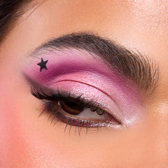 Close-up of a medium-skin eye with hot pink shadow and a stamped black star from the Best of Both Worlds palette