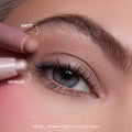 Close-up of a fair-skinned model’s blue eye wearing shimmery neutral shadow created with the All Eyes On Me Heart to Get Shadow Stix Set, showing matte and metallic cream eyeshadow tips applying blendable color on the eyelid.