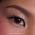 Close-up of a model’s brown eye wearing Heart to Get For Your Eyes Only Shadow Stix, showing soft metallic nude shimmer across the eyelid and lower lash line on smooth, natural skin, highlighting the creamy eyeshadow finish for US makeup shoppers.