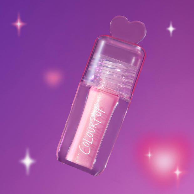ColourPop 2 Die 4 Ultra Glossy Lip in a clear tube with pink shimmer gloss and heart-shaped cap floating against a dreamy purple Heart to Get themed background with soft sparkles.