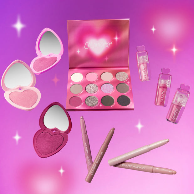 Heart to Get Full Collection makeup set featuring a pink heart-shaped eyeshadow palette, heart compact blushes, lip gloss tubes with heart tops, and neutral shadow sticks arranged on a glowing pink gradient background, perfect for romantic Heart to Get looks.