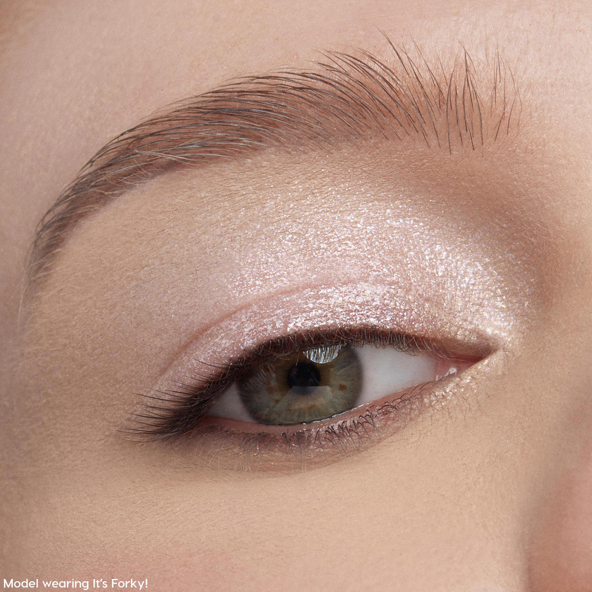 Shimmery eyelid wearing Play All Day Jelly Much Shadow, showing a metallic pale pink wash from ColourPop Jelly Much Shadow, applied across the lid and inner corner, catching light under a groomed brow in an extreme close-up beauty shot.