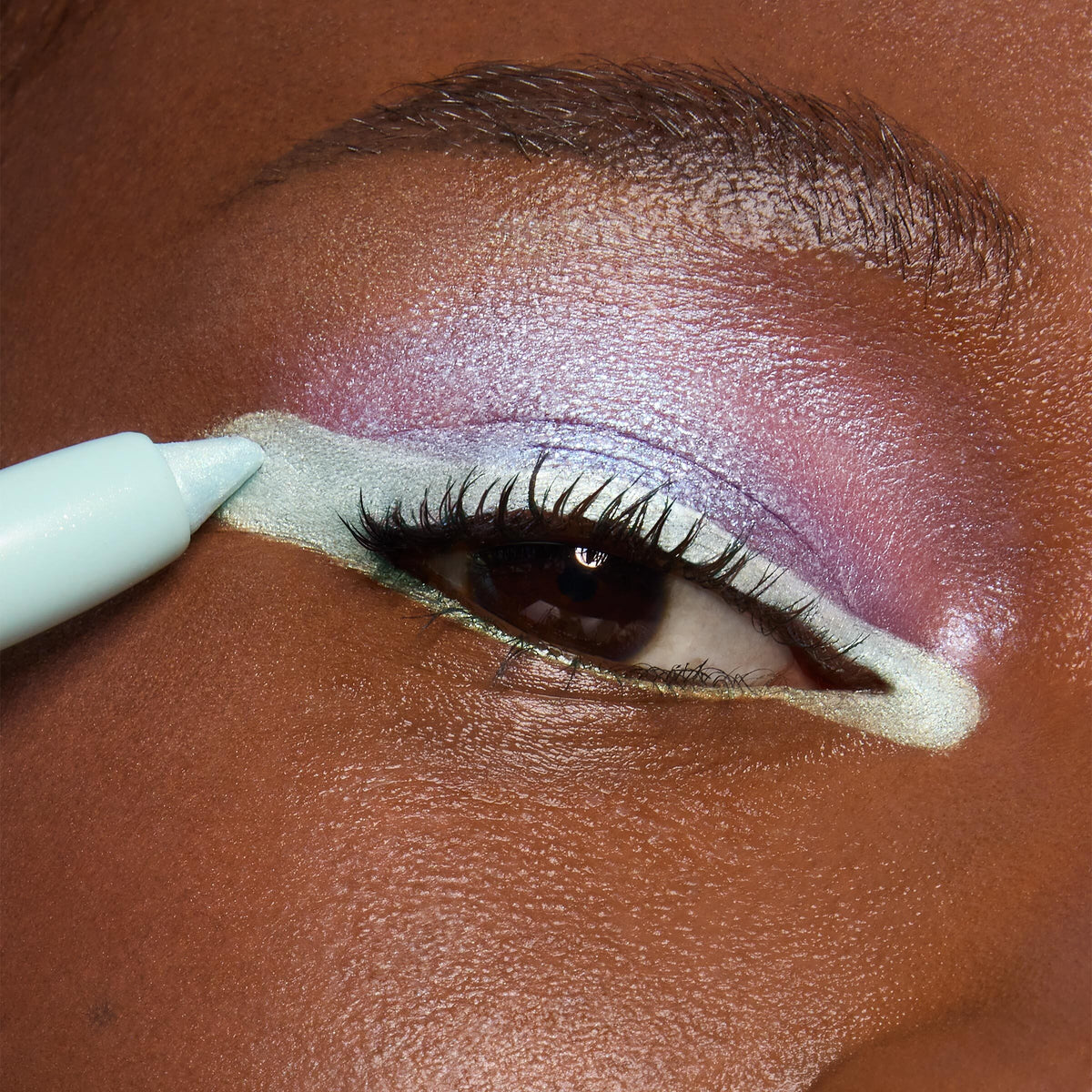 Mint eyeliner pencil lines a metallic seafoam outline on a close-up eye with iridescent lavender and pink shadow, showcasing the Disney Lilo and Stitch Collection from the ColourPop Full Collection Set.