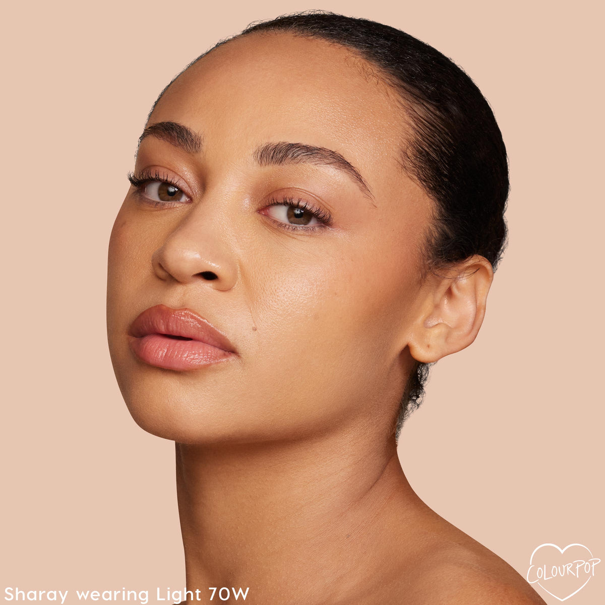 Model wearing Light 70 W, ColourPop Hyaluronic Hydrating Foundation, showing a smooth, dewy, warm‑toned complexion in a close-up studio portrait against a soft beige background.