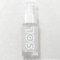 Like Diamonds pump bottle displaying iridescent micro-shimmer through frosted glass with bold white SOL logo, ColourPop SOL Shimmering Dry Oil, standing upright on a silver glitter backdrop that enhances the sparkle for a luminous body glow.