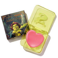 Heart-shaped pink True Love’s Form ColourPop Lip and Cheek Balm sits open in a translucent neon-yellow compact with an embossed S logo, placed beside its ColourPop x Shrek box featuring Princess Fiona artwork.