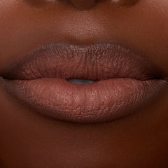 Lips wearing ColourPop Lippie Stix In the Nude, delivering creamy brown‑nude color with smooth, even coverage; macro studio close-up highlights hydrated texture and crisp lip line for an everyday lipstick look.