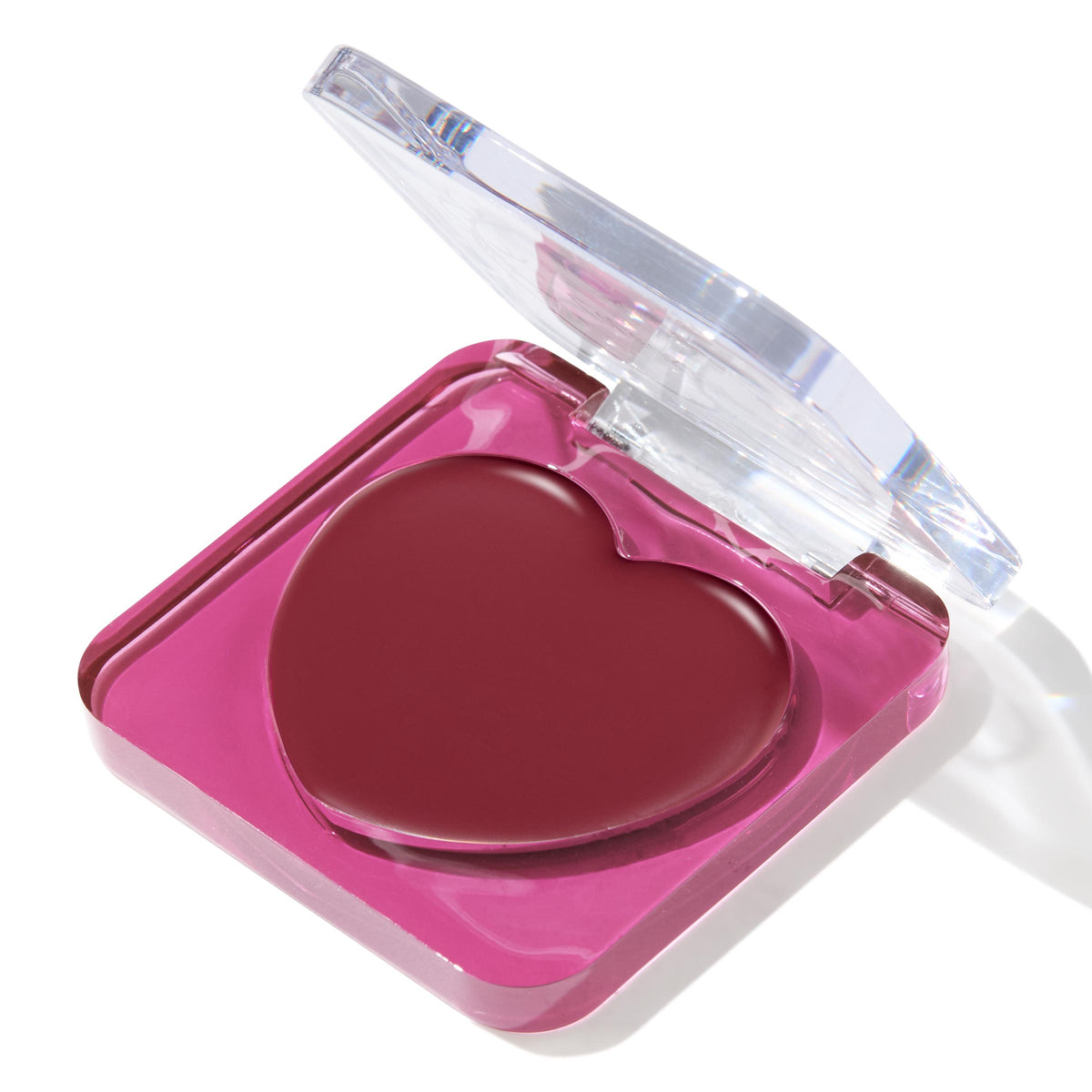 Heart-shaped Ravished ColourPop Lip and Cheek Balm resting in a hot pink square compact with a clear flip-top lid, shown three-quarter open on a white background, highlighting the deep berry cream tint for lips and cheeks.