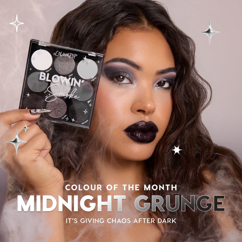 ColourPop Blowin’ Smoke 9-pan eyeshadow palette held beside a model’s face, showing cool-toned gray, silver, and black mattes and shimmers as she wears a dramatic smoky eye and glossy black lips in a misty, starry Midnight Grunge promo scene.