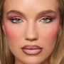 Model showcases rose-toned smoky eye created with the Smoke 'N Roses ColourPop Shadow Palette, featuring shimmery pink lids, deep mauve crease, winged liner, and long lashes, paired with soft pink blush and glossy nude lips in a studio close-up.