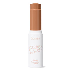 ColourPop Pretty Fresh Tinted Foundation Balm in Dark 18 - twist-up stick stands open with the warm deep shade bullet extended, housed in a white tube with peach lettering against a clean white background.