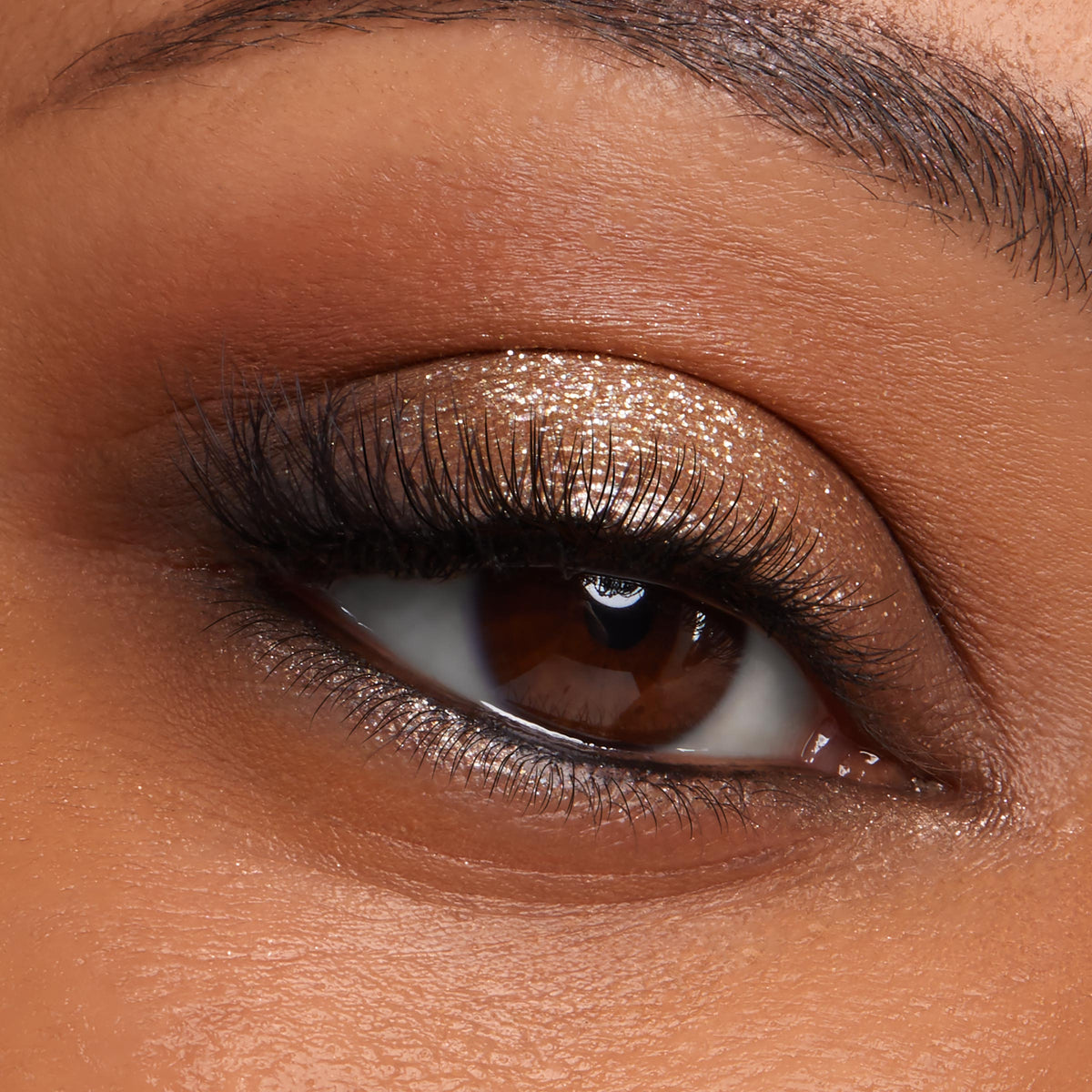 Bronze glitter eyeshadow gleams on a brown eye, lashes softly curled and inner corner highlighted, showcasing Metallic Mood ColourPop Shadow Palette & Brush Set with brush-blended metallic lid and warm matte crease.