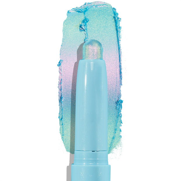 Colourpop Game Over Shadow Stix eye crayon gliding across a white background, leaving a bold metallic aqua, lavender, and mint duochrome shimmer swatch behind its pastel blue twist-up tube packaging.