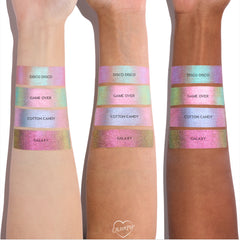 Colourpop Cotton Candy Shadow Stix swatch shown on three arms with different skin tones, displaying its pastel iridescent pink-blue shimmer stripe between other shades in the Shadow Stix collection for comparison.