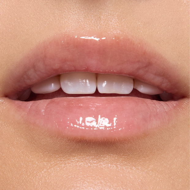 Glossed lips wearing Gumdrop Buttons Candy Lip Oil, showing a sheer high-shine pink tint from ColourPop Candy Lip Oil, captured in a tight on-model close-up under studio lighting.