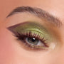 Close-up eye wearing shimmering ogre-green, olive, and chartreuse shadow with a sharp plum cut crease and lengthened lashes, showcasing the Shrek-Spress Yourself ColourPop Lip and Eye Set for bold green glam looks.