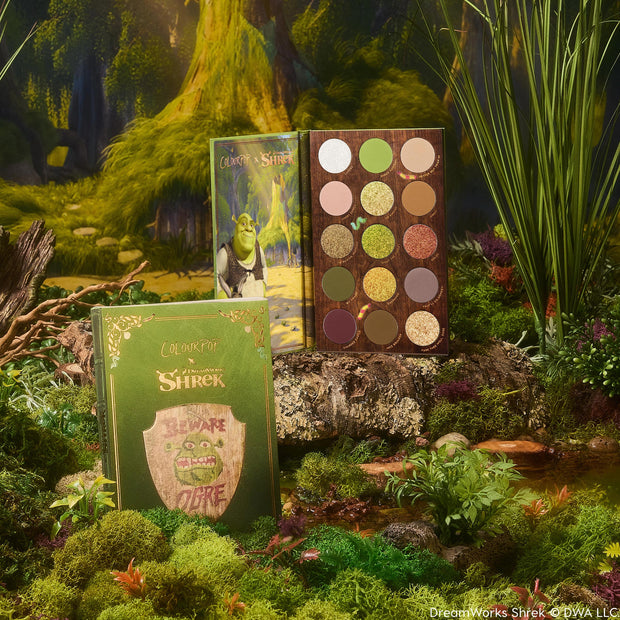 ColourPop Shadow Palette Beware Ogre opens to display 15 earthy green, brown, and gold mattes and shimmers, paired with a matching green box and Shrek artwork, styled in a mossy swamp setting.
