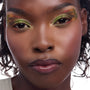 Model wearing Shrek-inspired eye look - lime and olive shadows with wavy brown edges and tiny red inner-corner dots - plus glossy plum lips - in a studio close-up, highlighting the ColourPop X DreamWorks Shrek Full Collection Set, a ColourPop Full Collection Set.