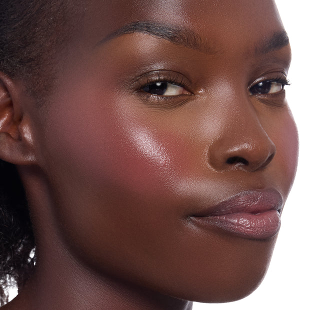 Fairytale Things ColourPop Lip and Cheek Balm adding a dewy rosy-plum flush to a model’s cheek and a soft sheen on lips, shown in a close-up beauty shot to highlight pigment payoff and glossy glow.