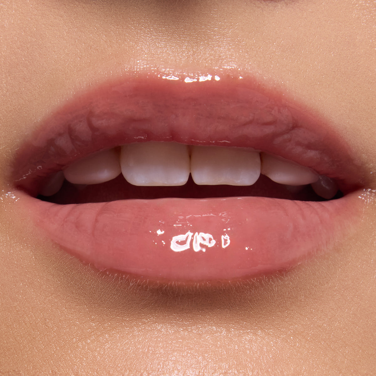 Glossy, close-up lips wearing ColourPop Ultra Glossy Lip in Totally Swamped, a sheer pink-nude shade, catching light with a glassy finish; teeth softly visible in an extreme macro beauty shot against natural skin.