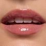 Glossy, close-up lips wearing ColourPop Ultra Glossy Lip in Totally Swamped, a sheer pink-nude shade, catching light with a glassy finish; teeth softly visible in an extreme macro beauty shot against natural skin.
