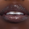 Shimmering lips wearing ColourPop Ultra Glossy Lip in Totally Swamped, a deep cool-toned gloss packed with multicolor sparkle, shown in an extreme close-up as the model parts their lips to reveal a high-shine, wet-look finish.