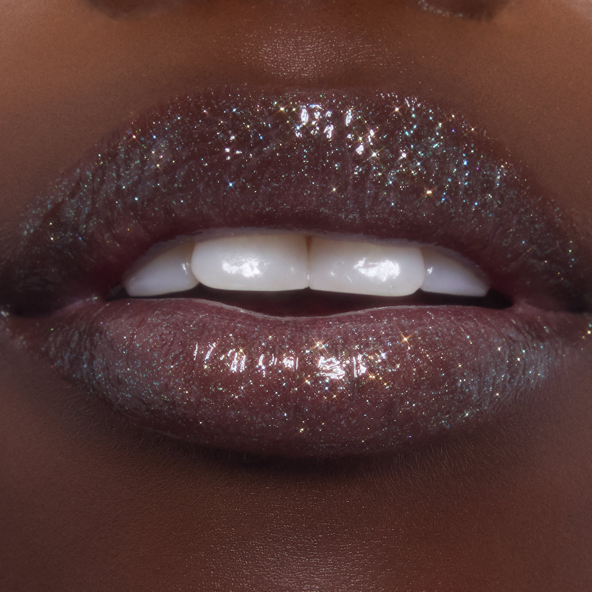 Shimmering lips wearing ColourPop Ultra Glossy Lip in Totally Swamped, a deep cool-toned gloss packed with multicolor sparkle, shown in an extreme close-up as the model parts their lips to reveal a high-shine, wet-look finish.