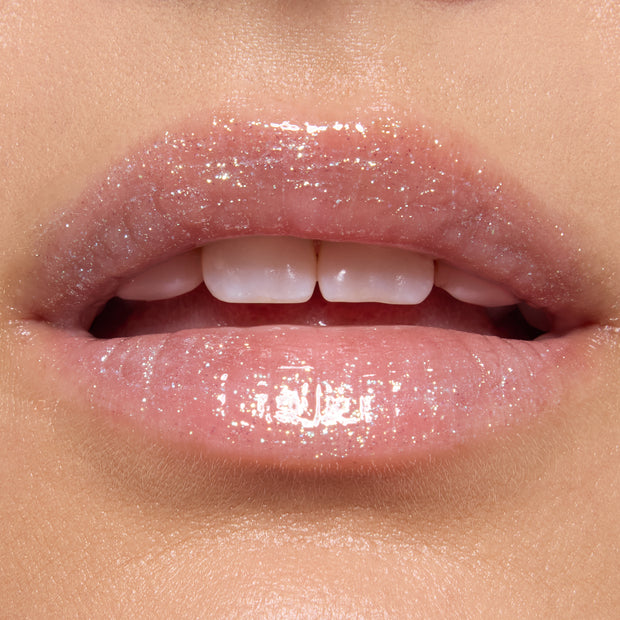 Lips wearing ColourPop Ultra Glossy Lip in Ogre, a sheer high-shine gloss with fine iridescent shimmer, reflecting light on smooth lips in an extreme close-up beauty swatch for product detail.