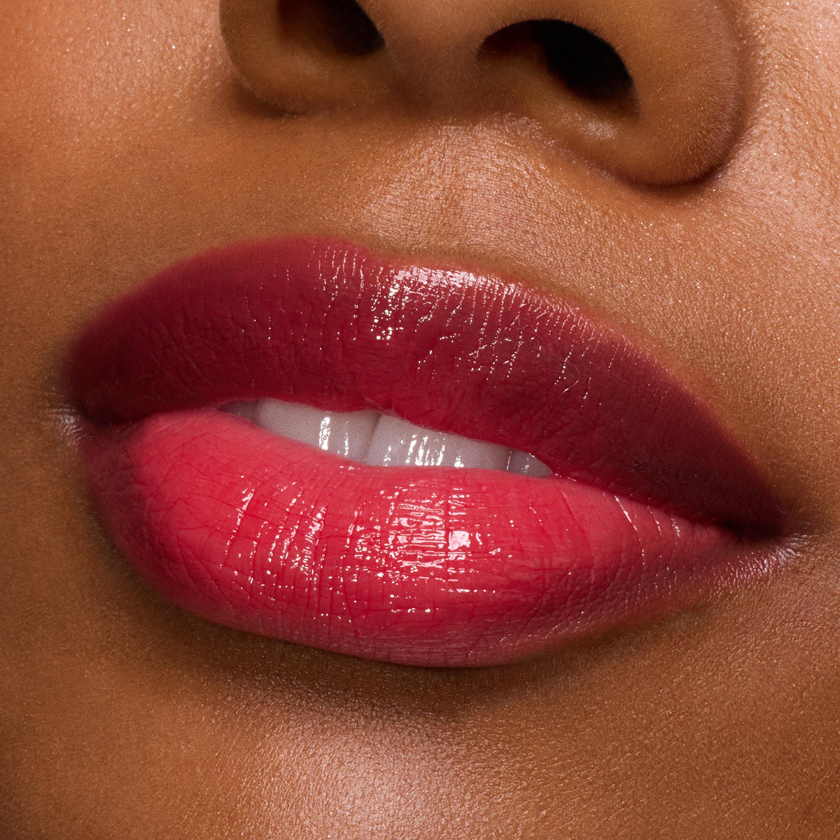 Glossy, plumped lips wearing ColourPop So Juicy Plumping Gloss in Spice Level, showing a sheer cherry-red shine with high reflection; macro close-up of a model’s mouth against smooth skin, highlighting hydration and a cushiony finish.